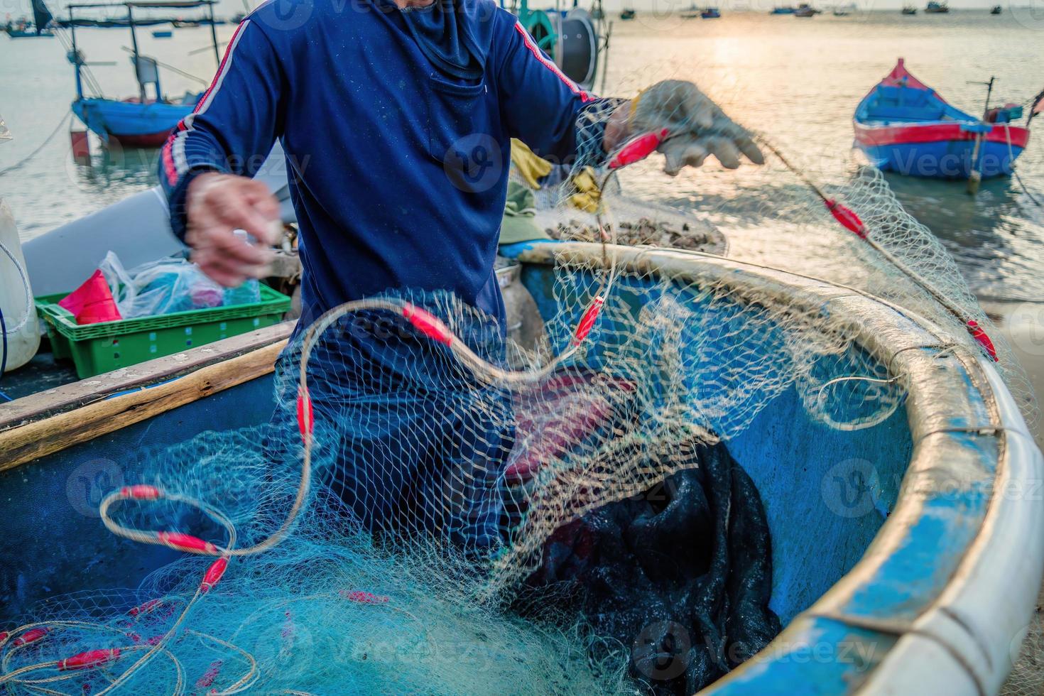 pêcheur jetant son filet au lever ou au coucher du soleil. les pêcheurs traditionnels préparent le filet de pêche photo