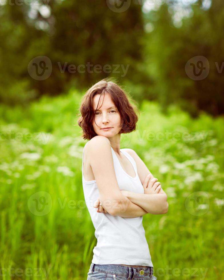 Belle jeune femme aux taches de rousseur avec les bras croisés dans le champ de l'été photo