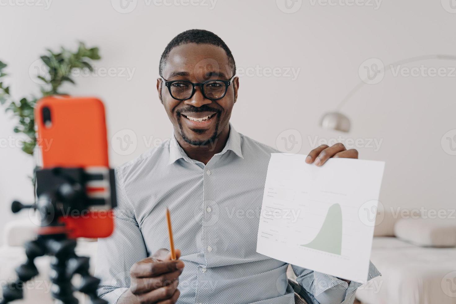 afro freelancer a un remue-méninges en ligne. un homme positif montre un tableau de données s'exprimant lors d'une conférence en ligne. photo