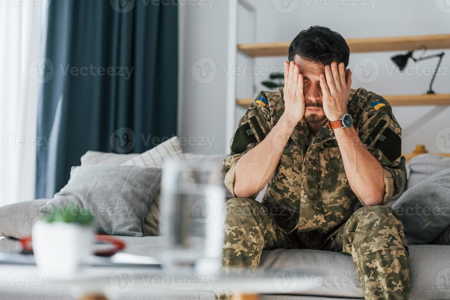 sur le canapé. trouble de stress post-traumatique. soldat en uniforme assis à l'intérieur photo