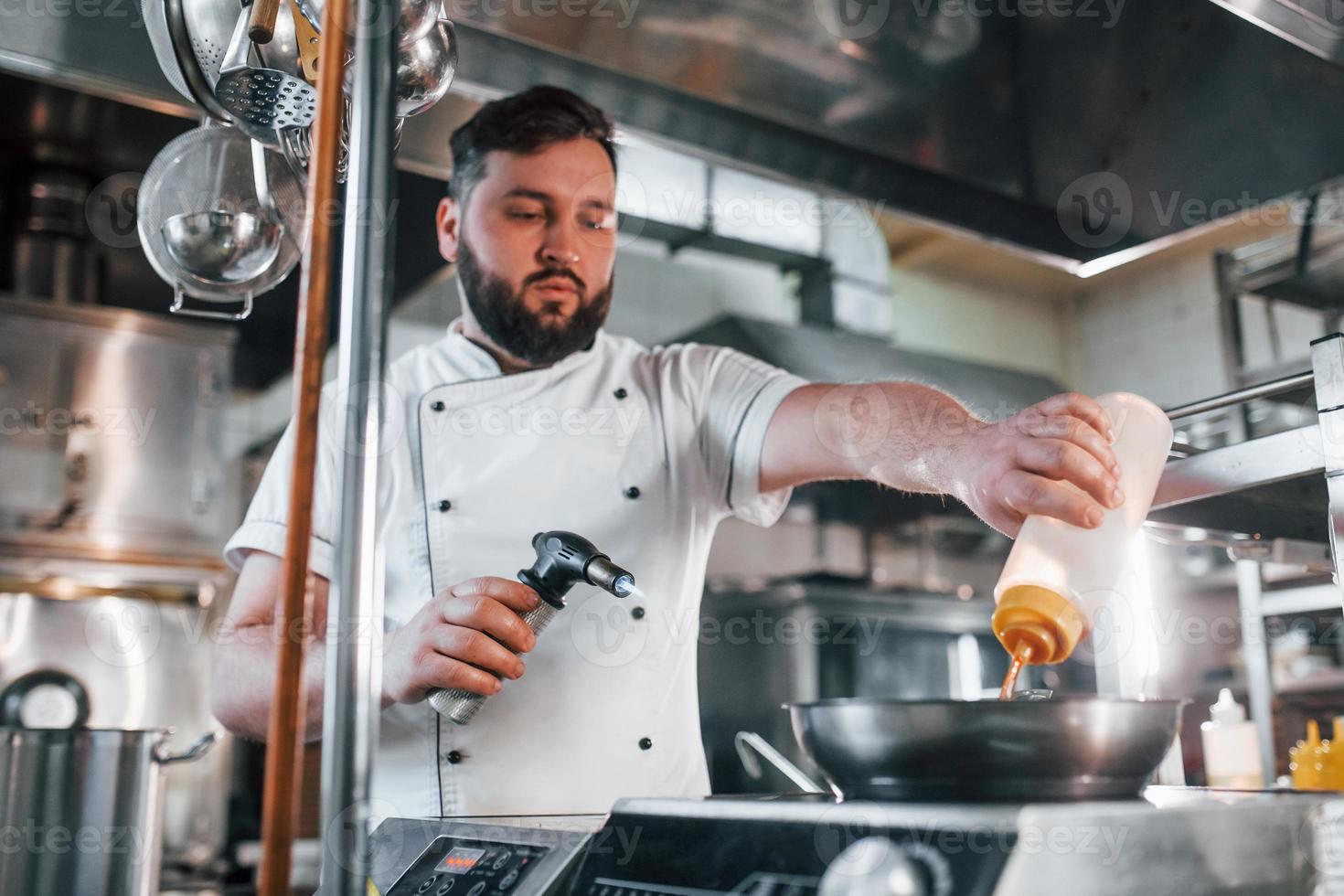 flammes dans la poêle. chef professionnel préparant la nourriture dans la cuisine photo