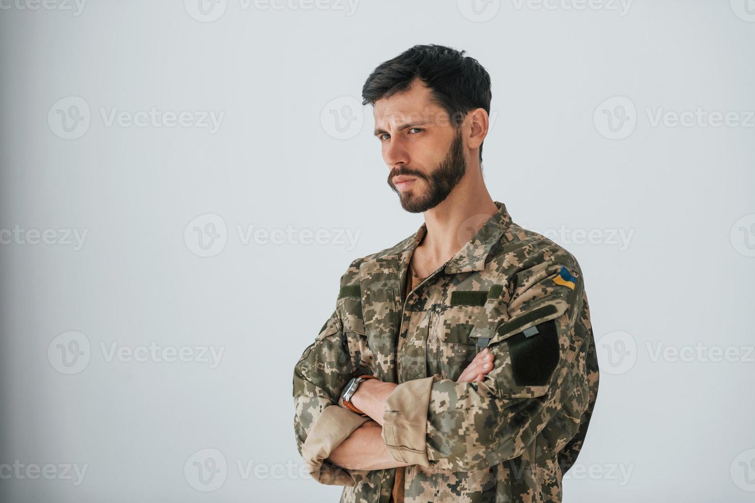 soldat en uniforme se tient à l'intérieur contre un mur blanc photo