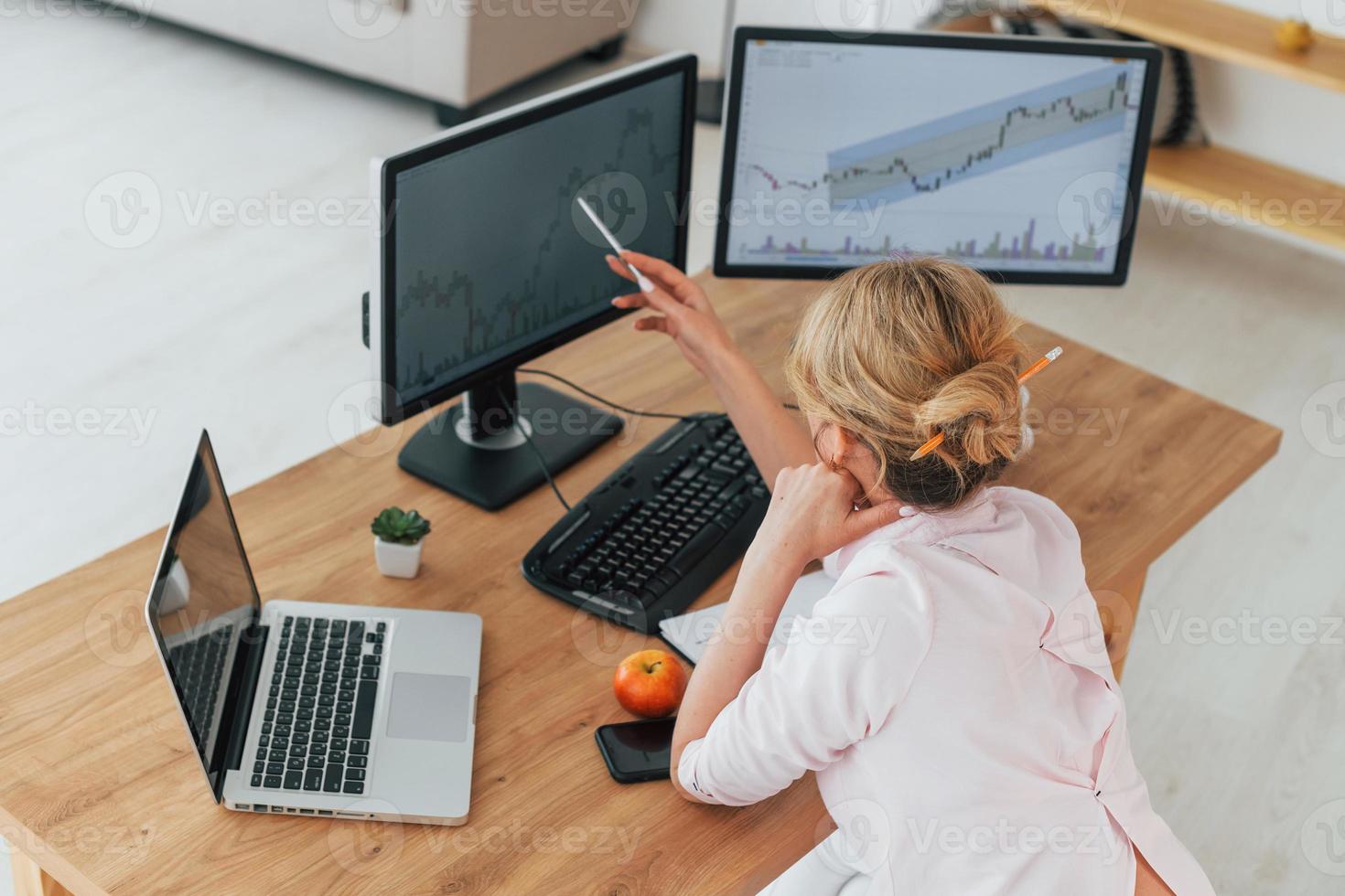 vue arrière. femme courtier en valeurs mobilières en tenue de soirée travaille au bureau photo