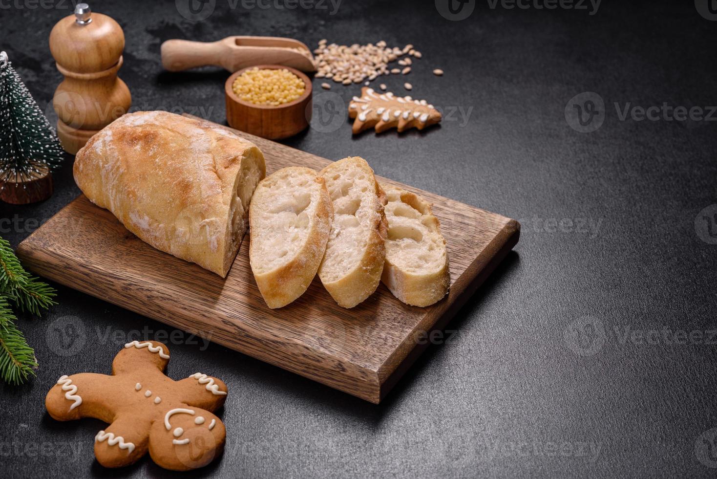 pain baguette français tranché sur une planche à découper en bois sur un fond de béton foncé photo