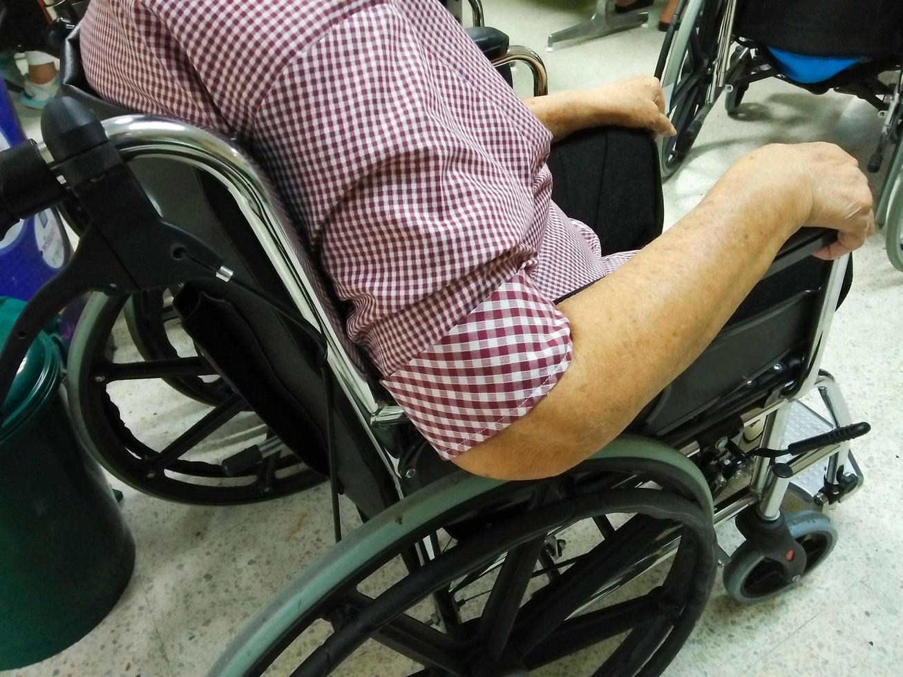 une vieille dame âgée ou âgée est assise sur un fauteuil roulant à l'hôpital en attente de traitement. photo