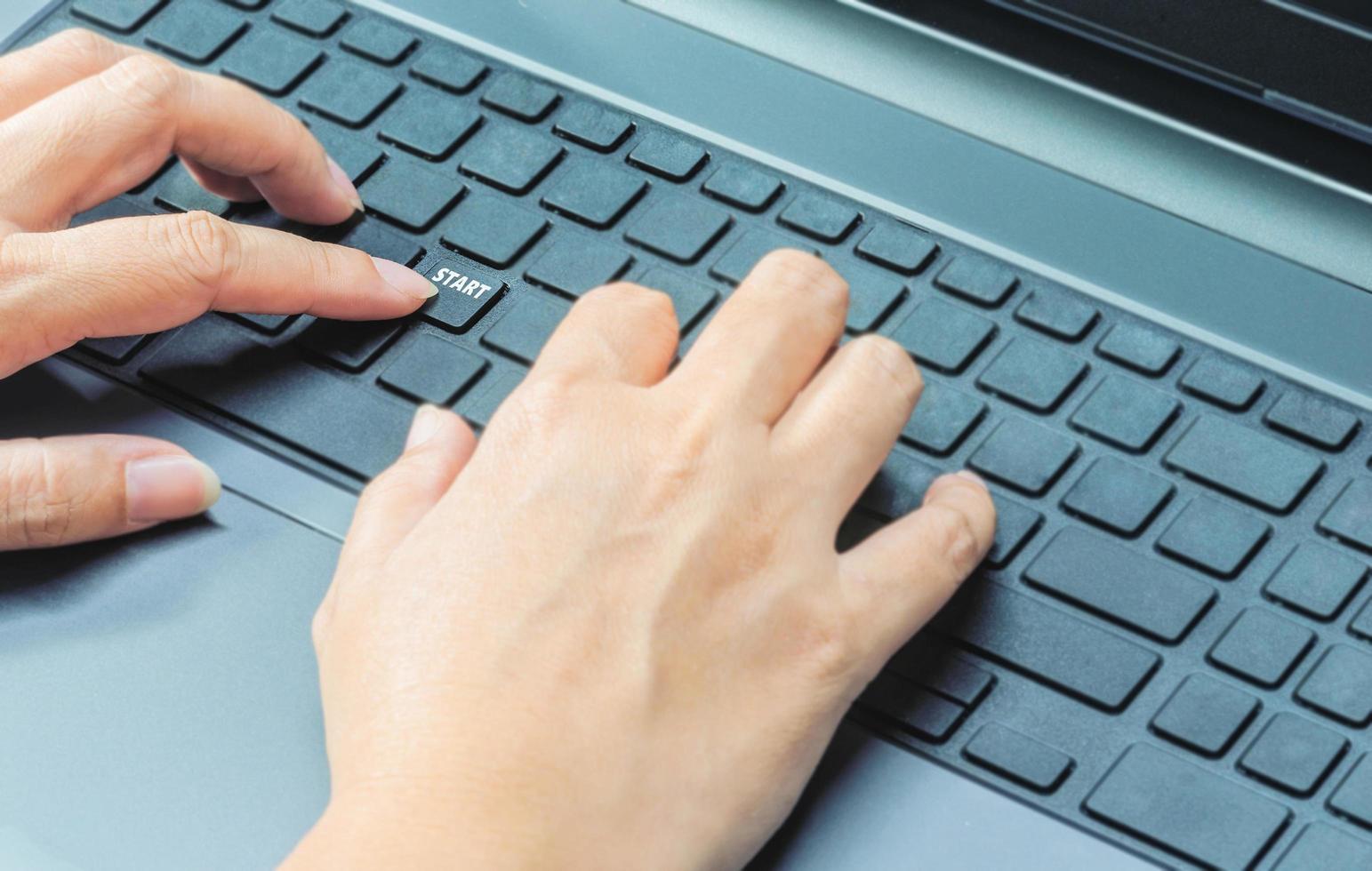 doigts féminins appuyez sur le bouton de démarrage sur un clavier d'ordinateur portable, concept de bureau d'affaires photo