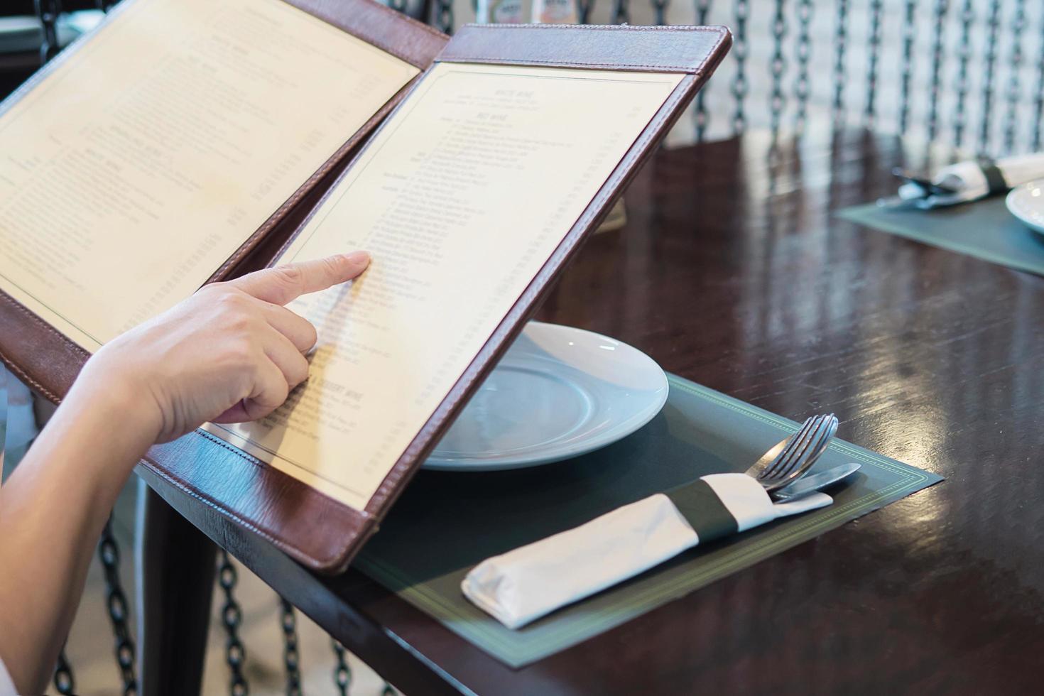 femme choisit de la nourriture dans un menu à commander au restaurant photo