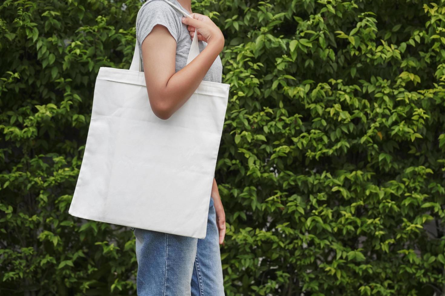 femme hipster avec sac en coton blanc sur fond de feuille verte photo