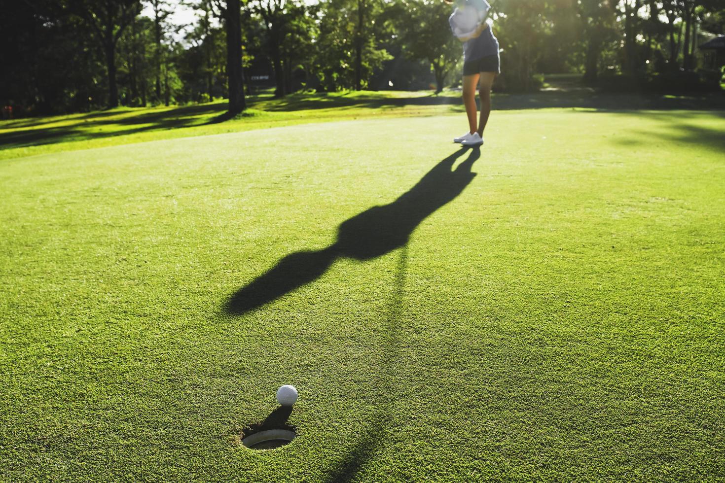 joueur de golf mettant une balle de golf dans un trou photo