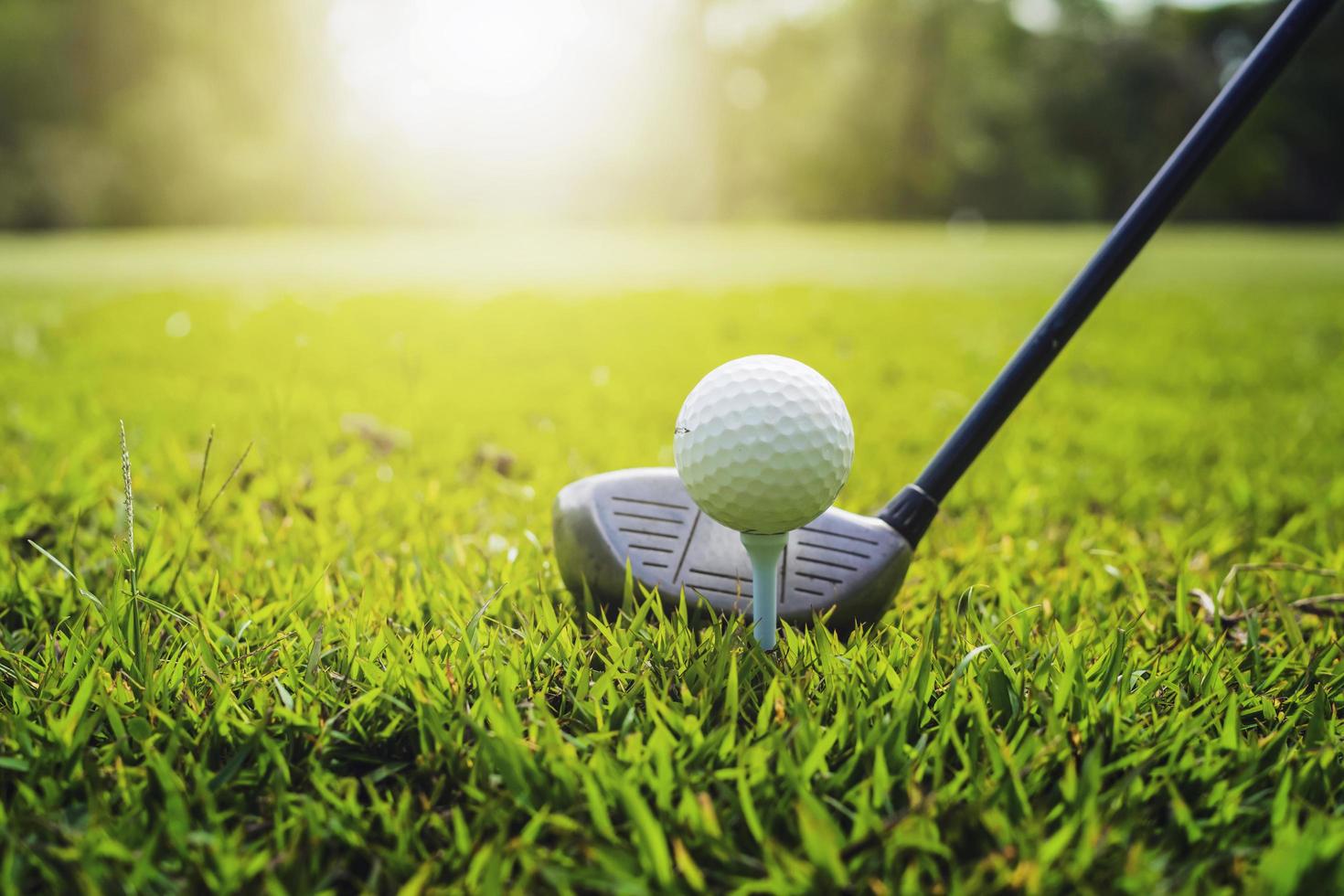 gros plan club de golf et balle de golf sur l'herbe verte avec coucher de soleil photo