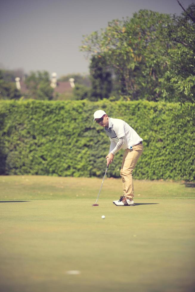joueur de golf au green frappant la balle dans un trou.couleur vintage photo