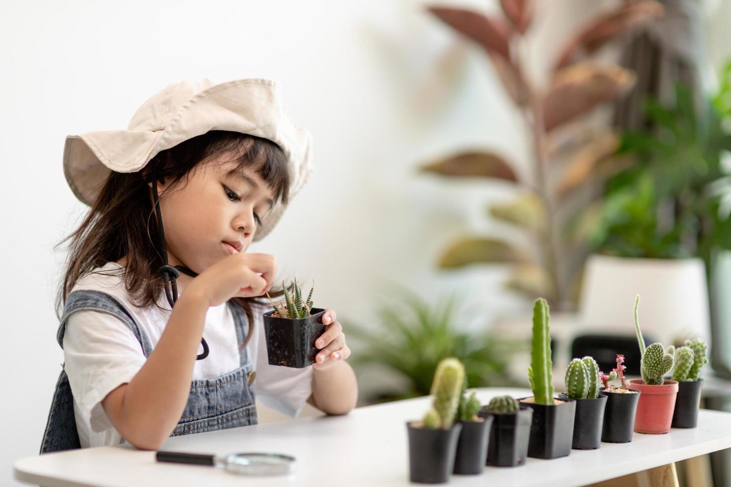 l'enfant touche doucement la nouvelle tige du cactus qu'il grandit avec soin, une main tient une loupe. concept d'éducation à la nature, de montessori et d'observation. photo