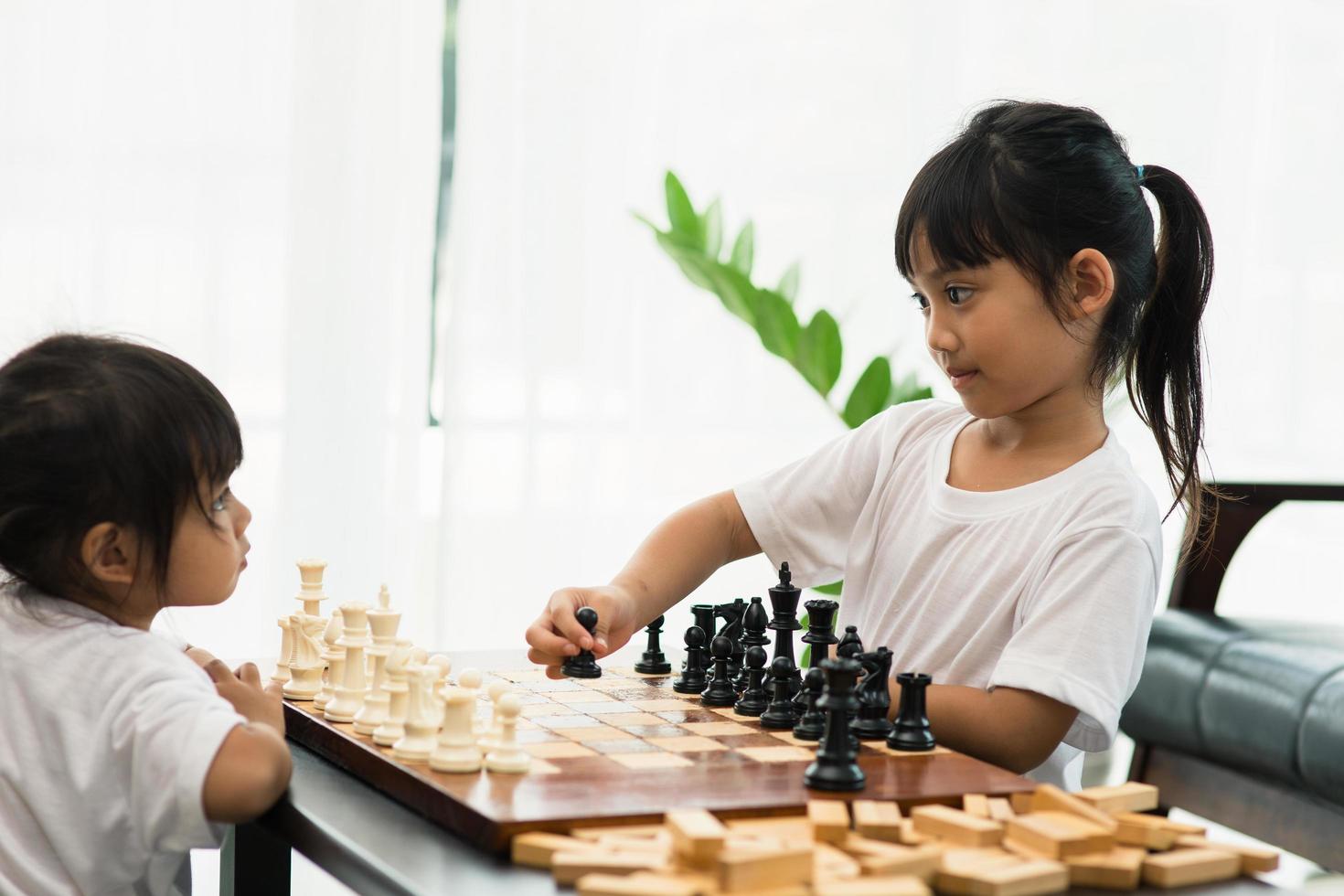 deux enfants mignons jouant aux échecs à la maison photo