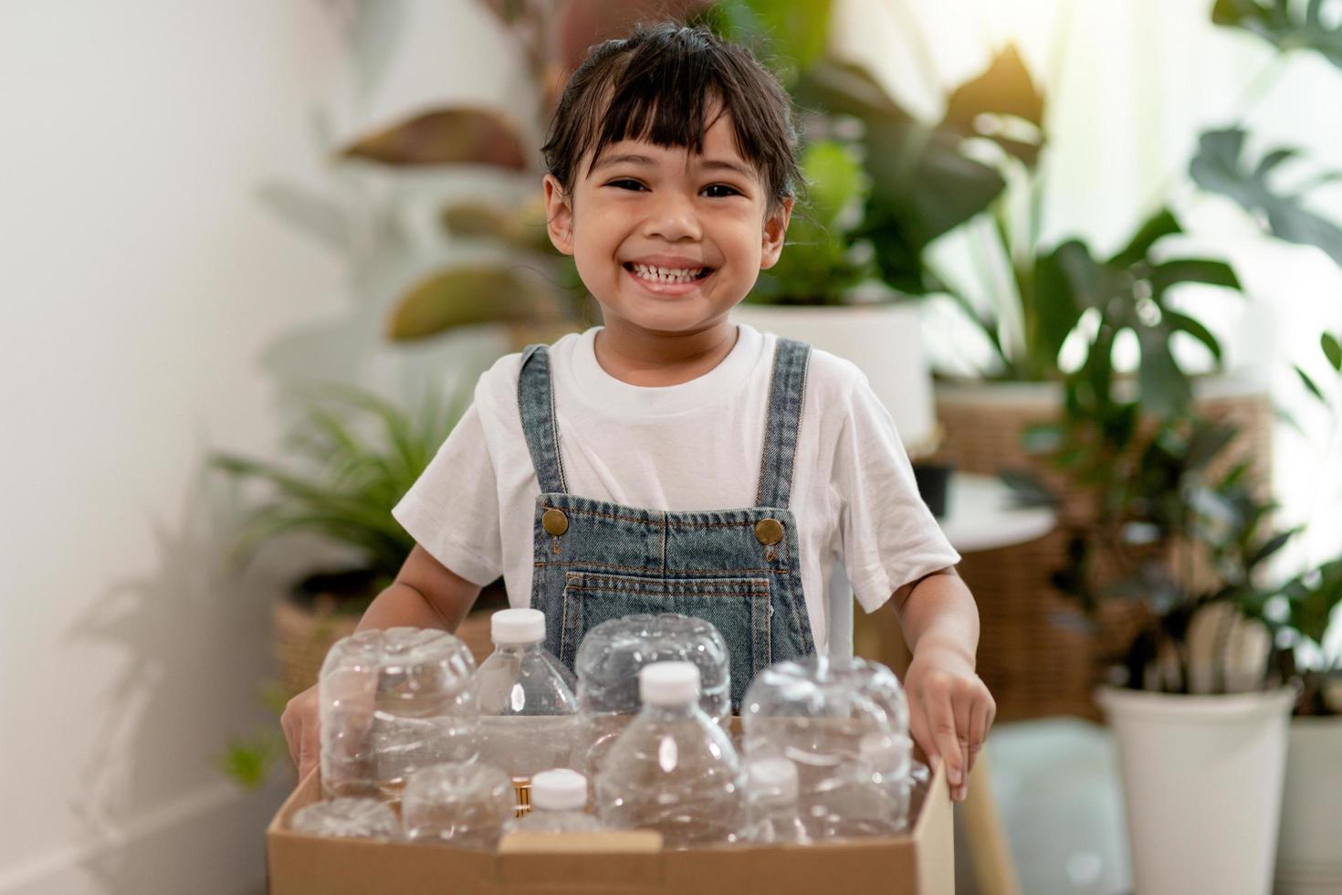 fille regardant la caméra et tenant des bouteilles en plastique pour le recyclage photo