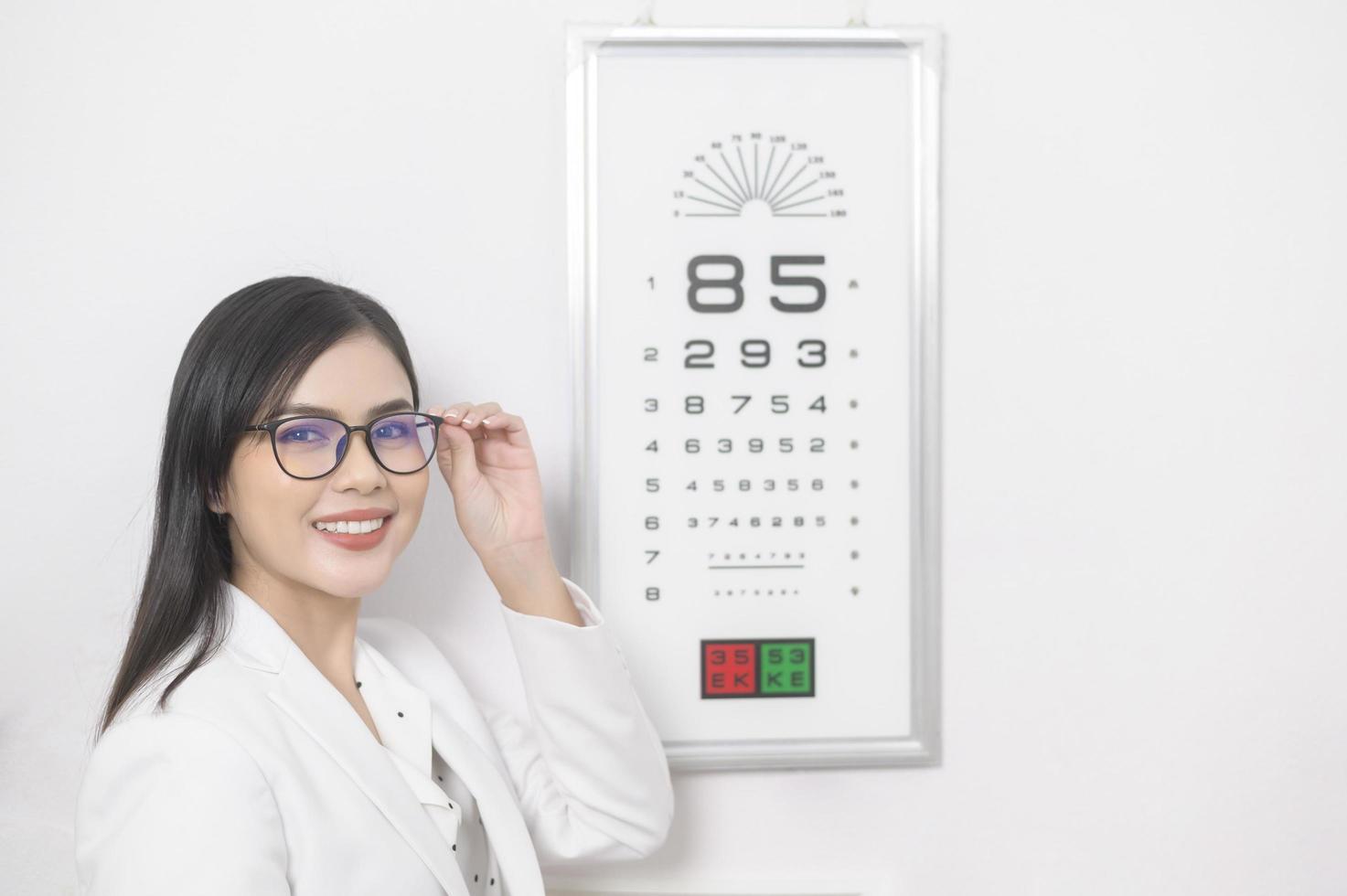 jeune ophtalmologiste faisant un test visuel pour le client à l'aide d'un tableau des yeux dans un centre optique, concept de soins oculaires. photo