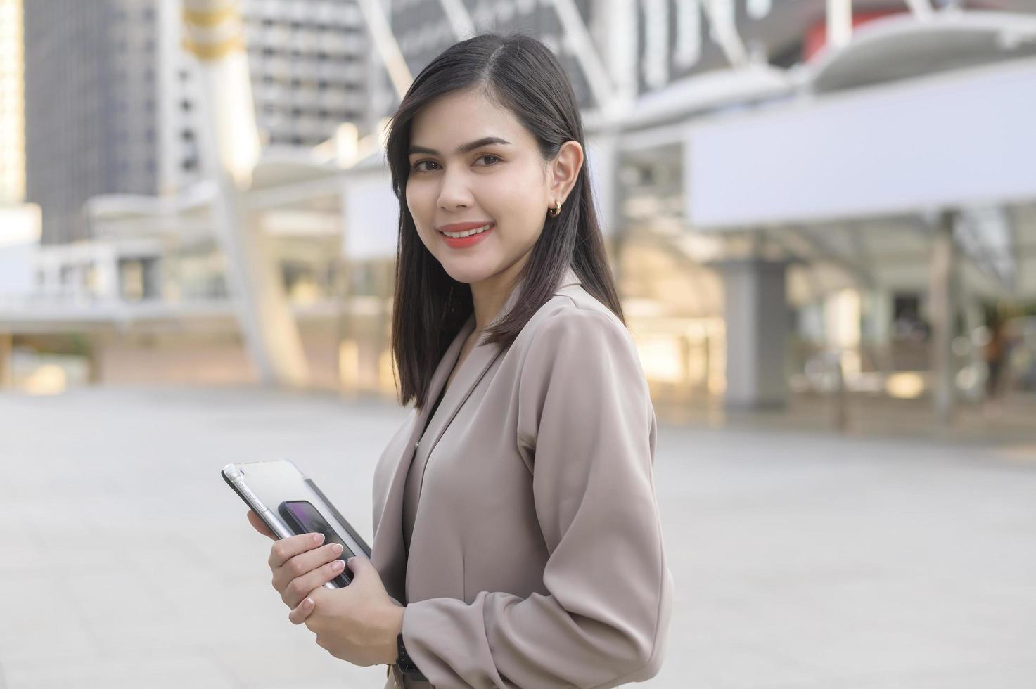 une belle jeune femme d'affaires utilise une tablette dans la ville moderne, la technologie d'entreprise, le concept de style de vie urbain photo