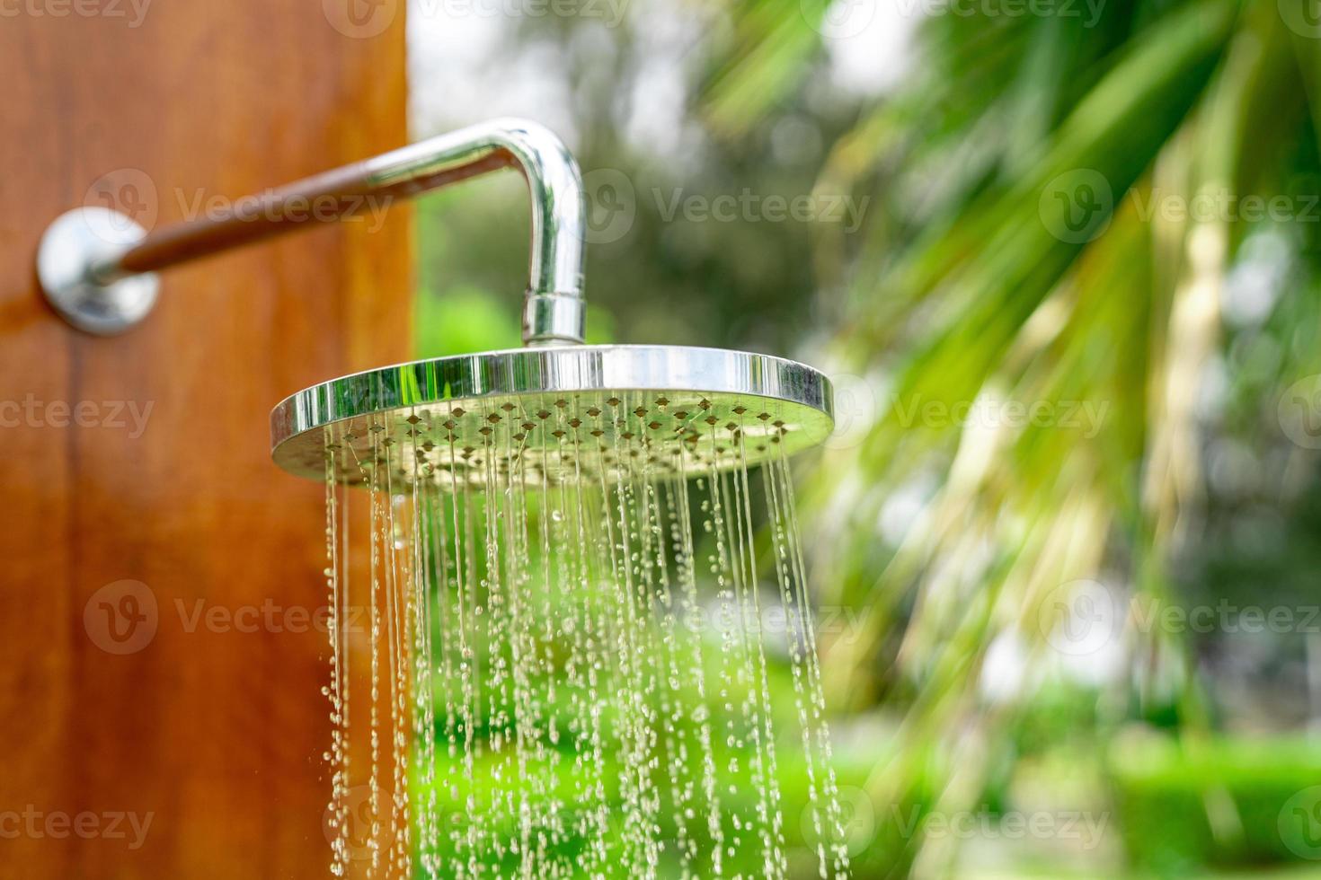 bâton de pommeau de douche extérieur sur la conception de poteau de plaque en bois pour le corps de douche avant de sauter dans la piscine du complexe. photo