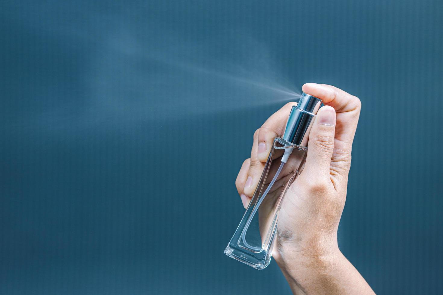 jeune femme pulvérisant du parfum sur fond bleu, gros plan photo