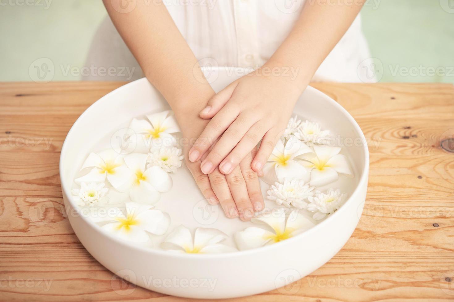 traitement de spa et produit pour les pieds féminins et le spa des mains. fleurs blanches dans un bol en céramique avec de l'eau pour l'aromathérapie au spa. photo