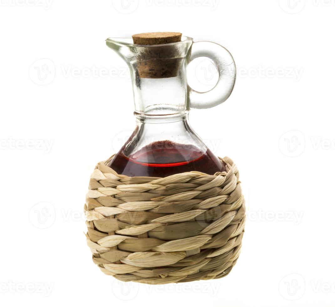 Petite carafe avec du vinaigre de vin rouge isolé sur le blanc photo
