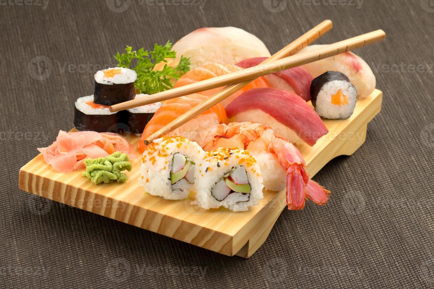 sushi et baguettes sur plaque de bois photo
