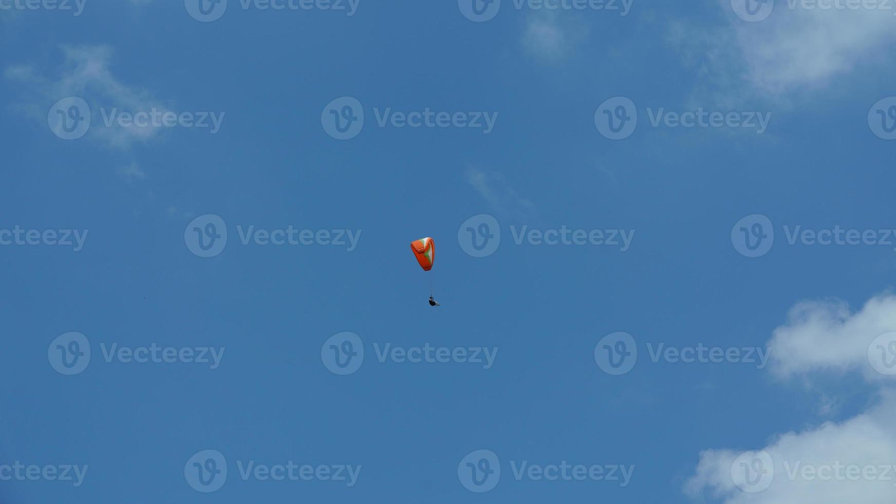 un parapente volant dans le ciel bleu avec des nuages blancs photo