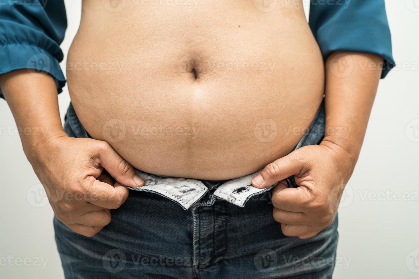 une femme asiatique en surpoids montre un gros ventre au bureau. photo