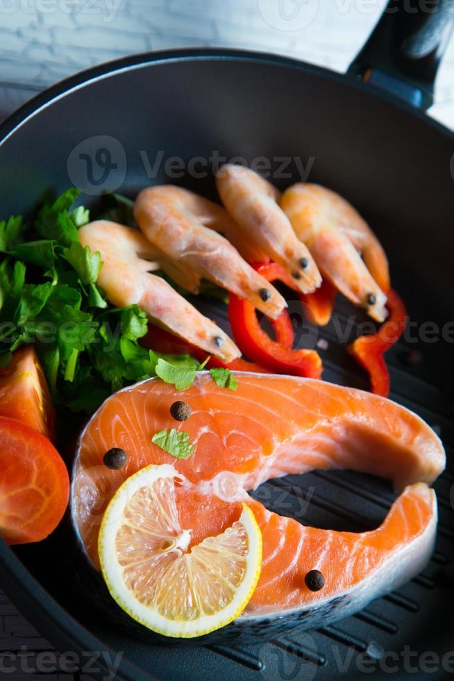 steak de saumon frais dans une poêle crevettes grillées et légumes photo