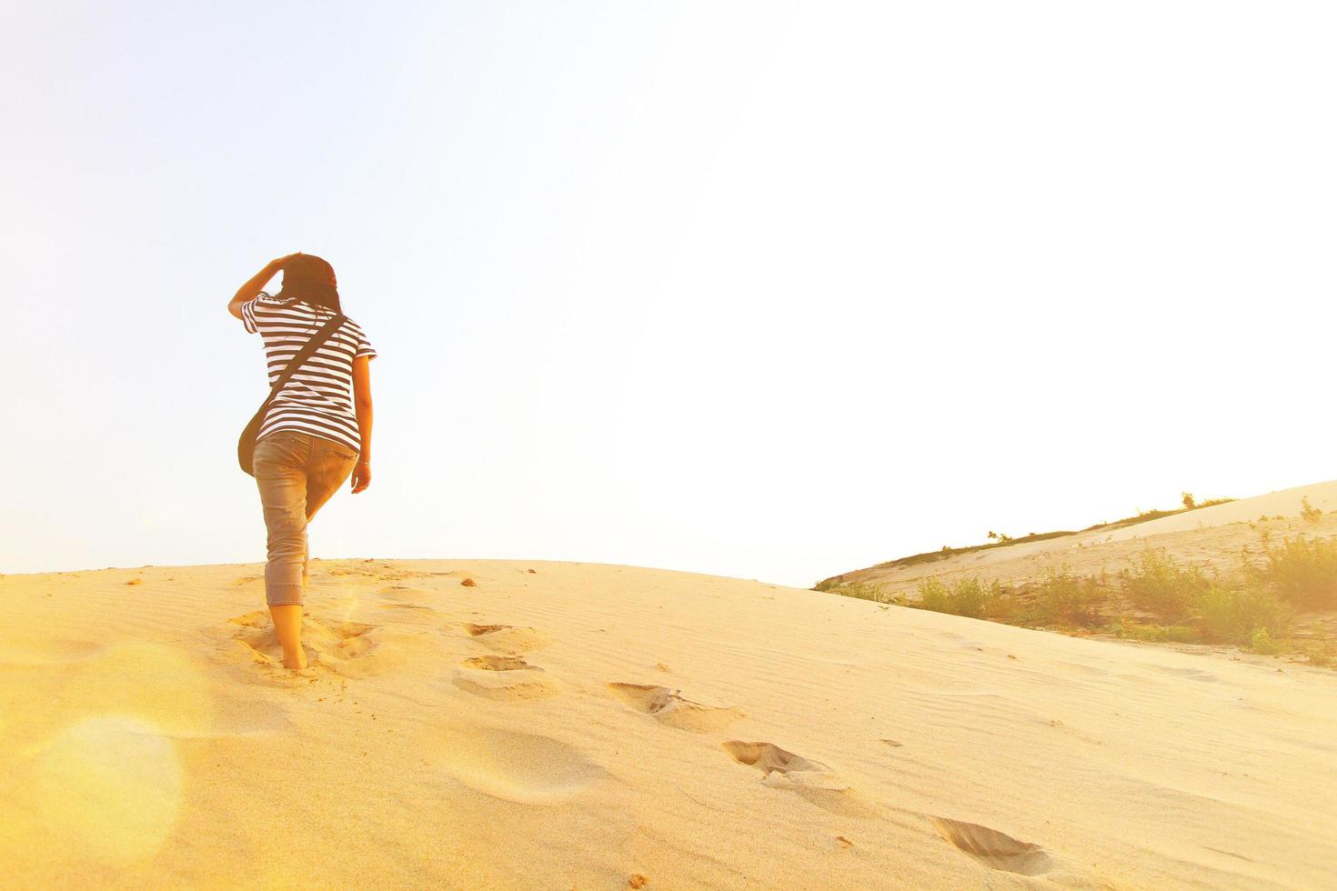 femme asiatique marchant dans le désert avec de nombreuses empreintes sur le sable avec lumière du soleil et espace de copie à sam phan bok, ubonratchathani, thaïlande. les gens appellent le grand canyon de thaïlande et lieu célèbre photo