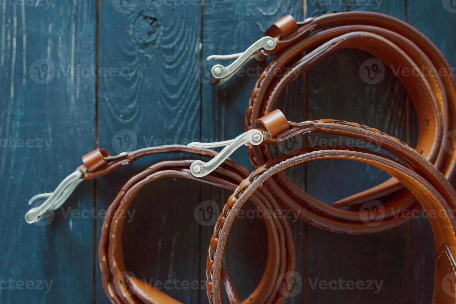 Trois ceintures en cuir marron foncé sur fond de bois photo