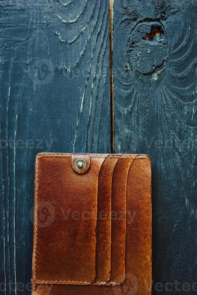 Portefeuille vintage artisanal en cuir sur fond de bois gris photo