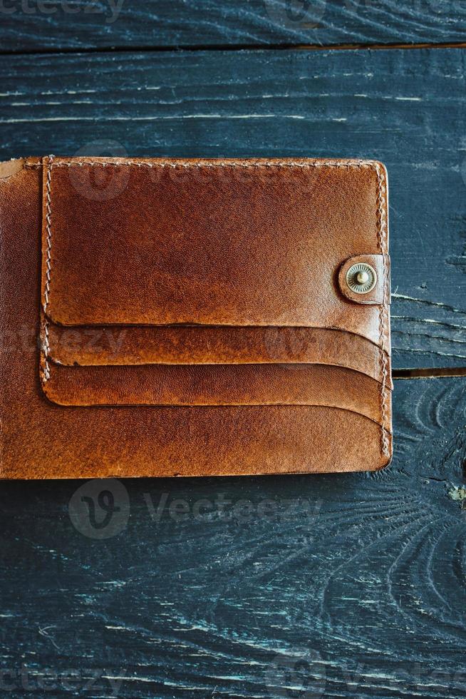 Portefeuille vintage artisanal en cuir sur fond de bois gris photo