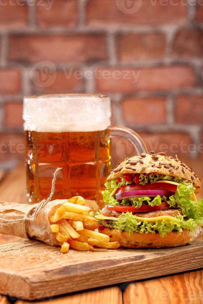 Hamburger grillé avec frites et bière sur fond de mur de brique photo