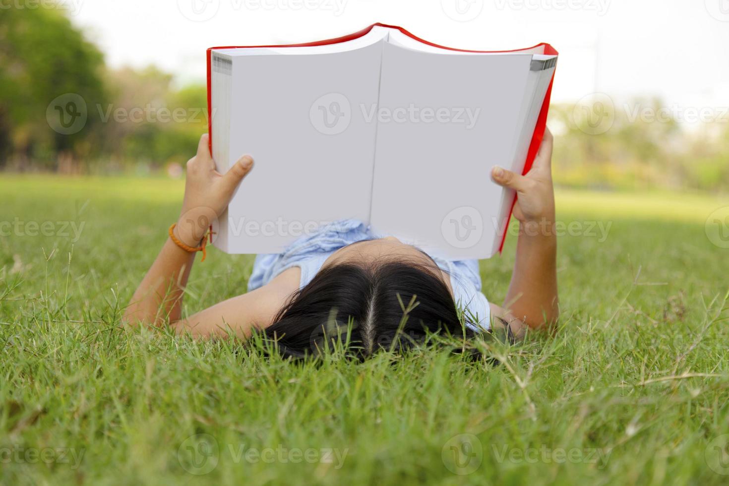 petite fille asiatique lisant un livre dans le parc photo