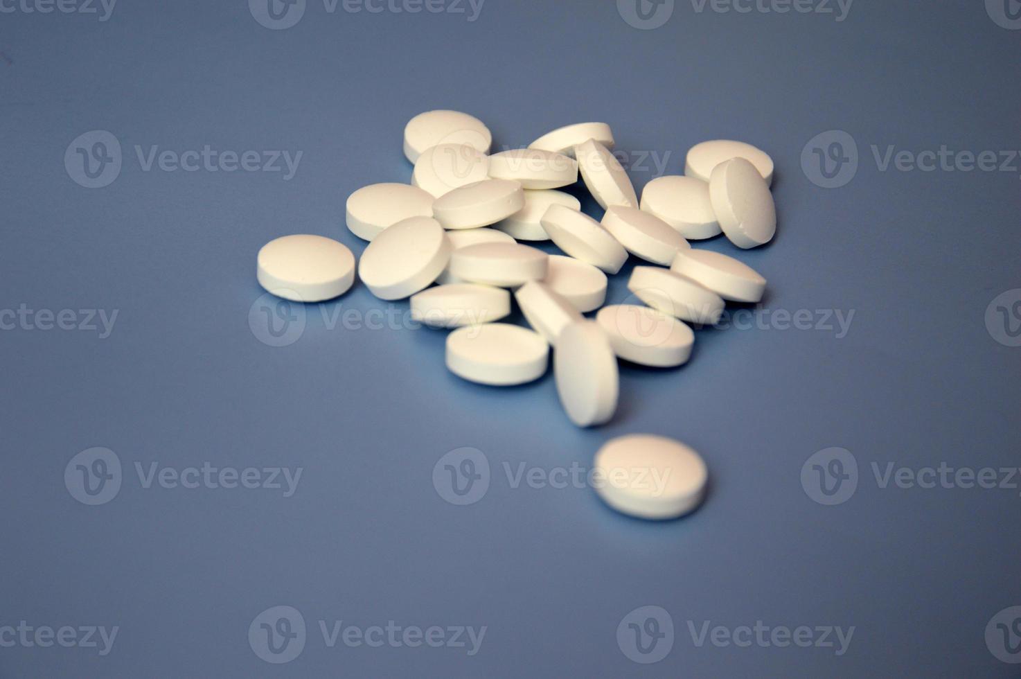 un tas de pilules sur ordonnance. les pilules blanches sont lâchement éparpillées sur un fond bleu. vitamines, médicaments, traitement. espace libre pour le texte. photo