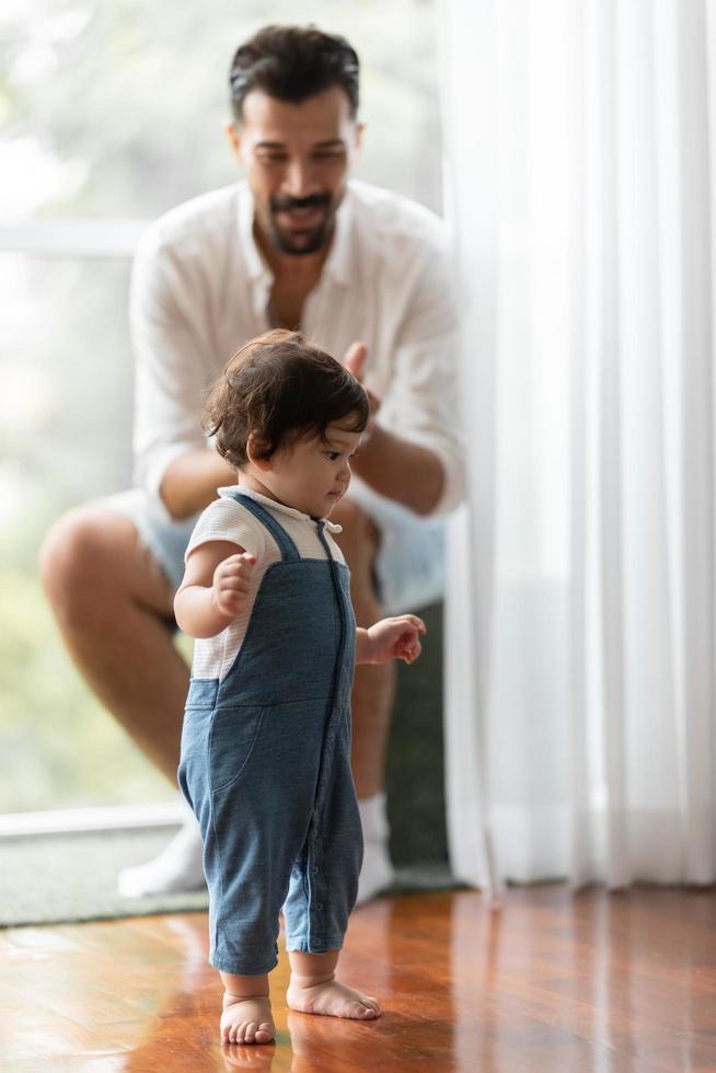 concept de famille de petit enfant mignon tout-petit, bébé apprenant à marcher avec le père et la mère pour aider à prendre soin et à tenir la main, première étape avec le soutien des parents d'enfance, petit portrait d'amour petit garçon à la maison photo