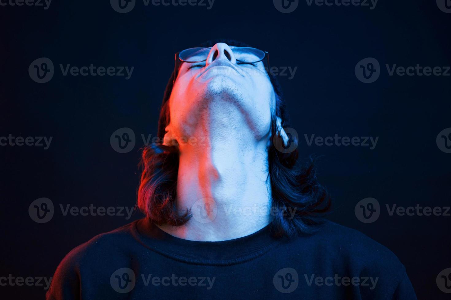 mettre la tête haute. studio tourné en studio sombre avec néon. portrait d'homme sérieux photo