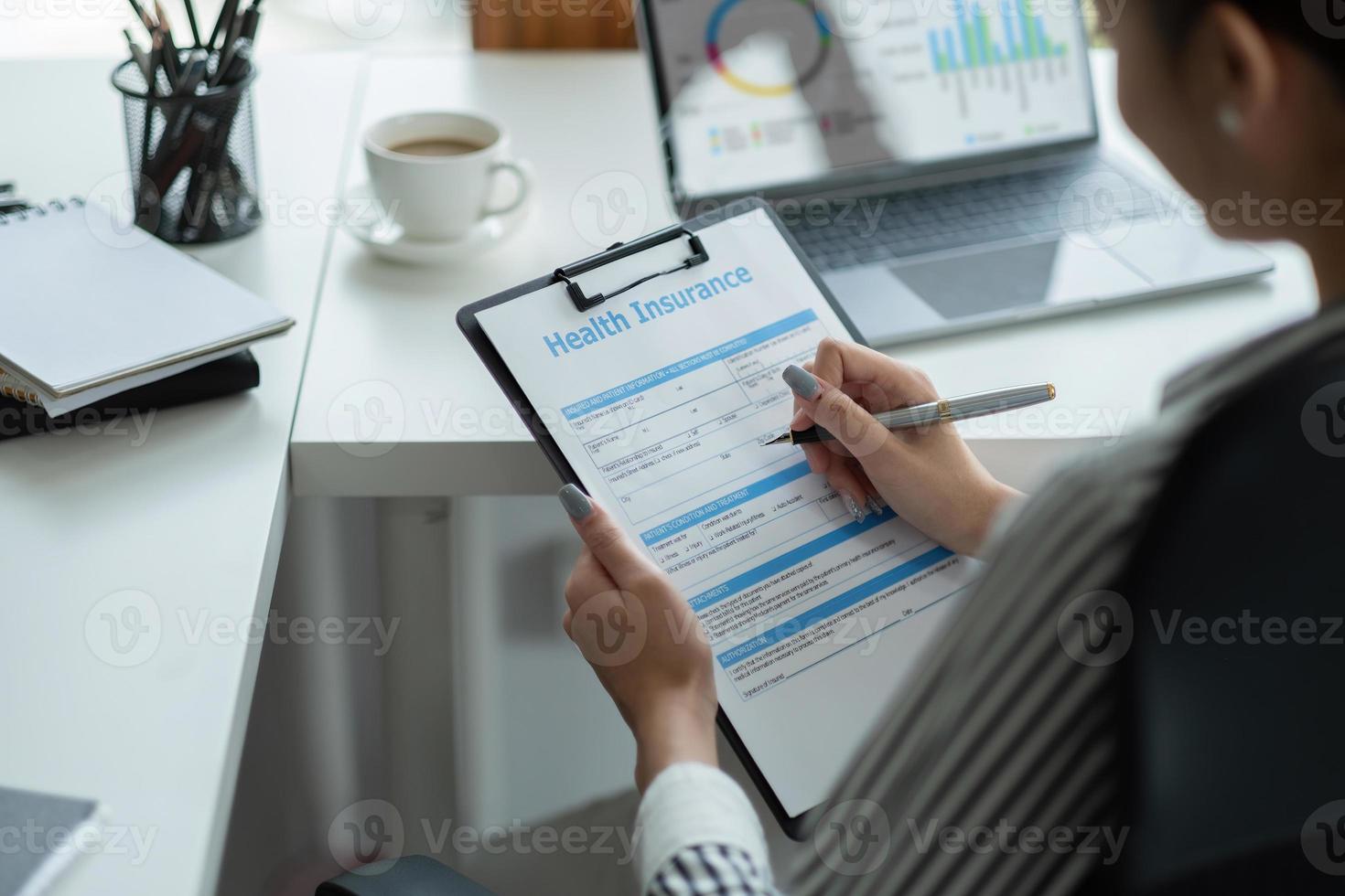 une femme asiatique examine et signe la demande d'assurance maladie. photo