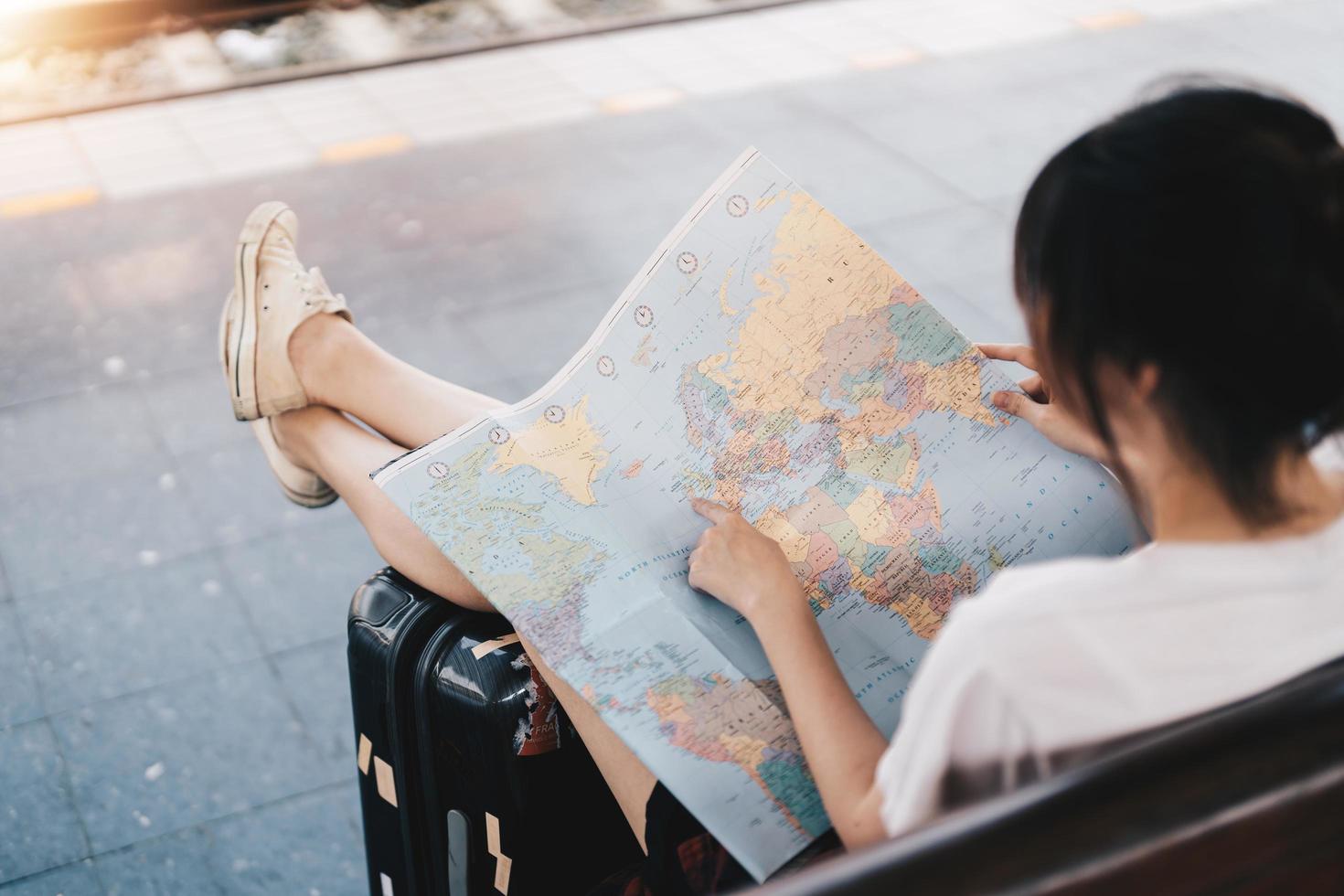 verso d'une voyageuse cherchant la bonne direction sur la carte, voyageant le long de l'asie en train, liberté et concept de mode de vie actif photo