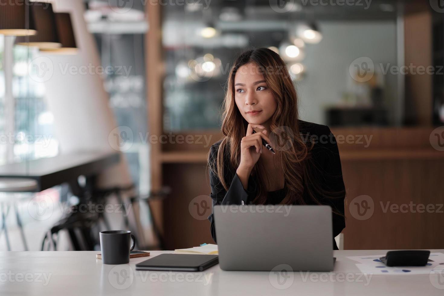 belle femme asiatique pensant idée et travaillant avec un ordinateur portable pour les finances dans un bureau moderne photo