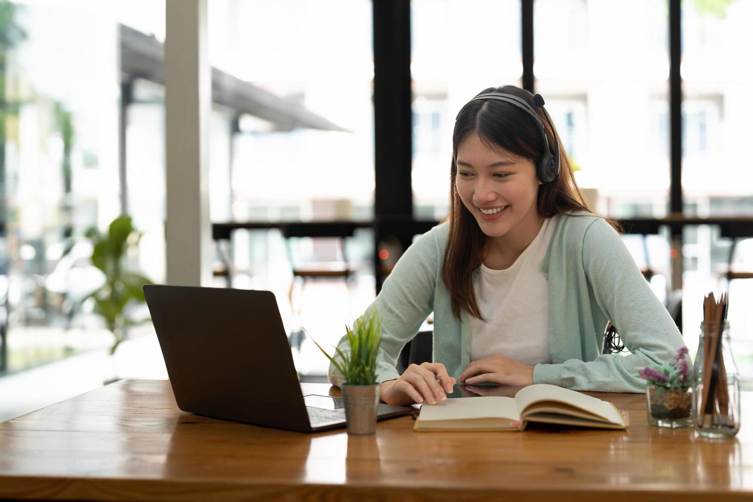 femme asiatique écrivant faisant la liste prenant des notes dans le bloc-notes travaillant ou apprenant sur un ordinateur portable à l'intérieur - cours éducatif ou formation, séminaire, concept d'éducation en ligne photo