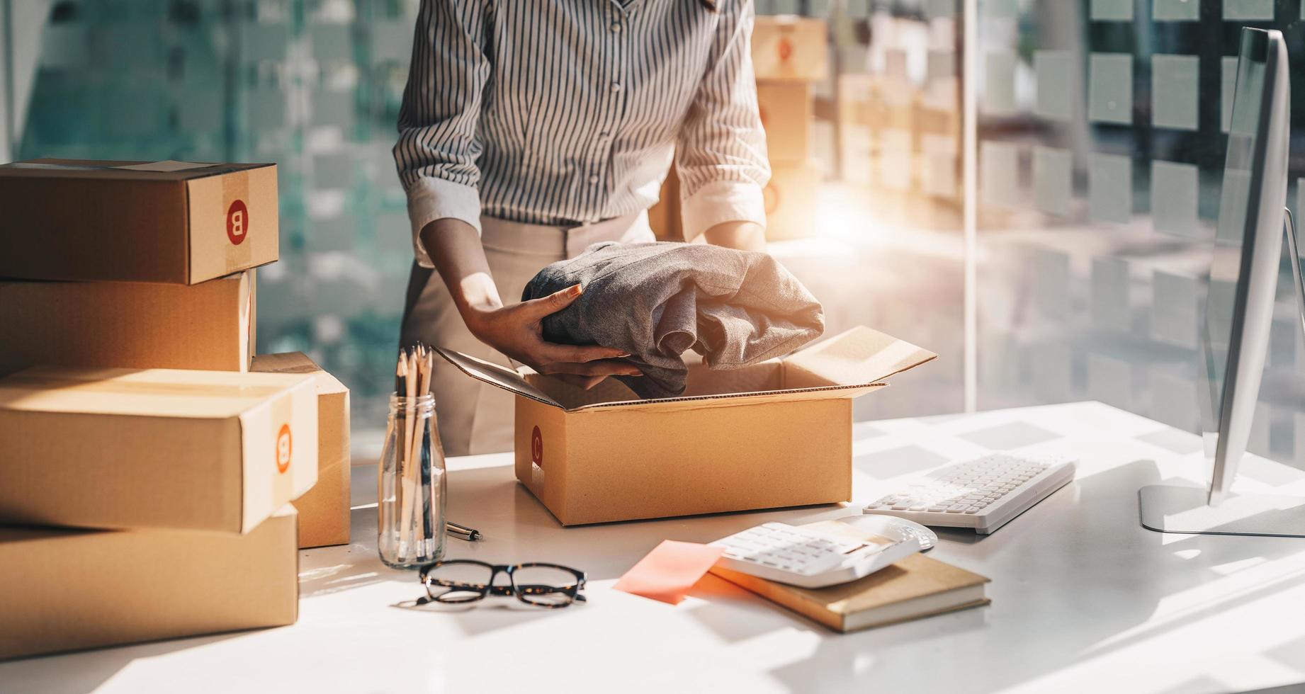 femme indépendante travaillant avec des vêtements d'emballage, entrepreneur en démarrage propriétaire d'une petite entreprise à la maison, emballage de vendeur en ligne et concept de livraison photo