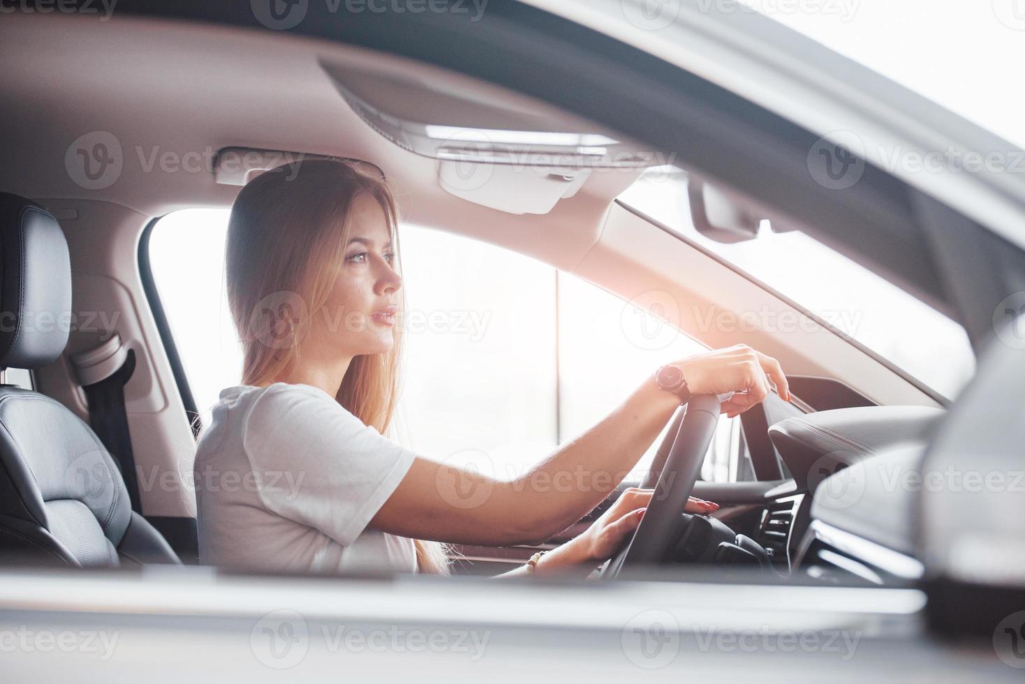 avec montre à portée de main. fille en voiture moderne dans le salon. le jour à l'intérieur. achat d'un véhicule neuf photo