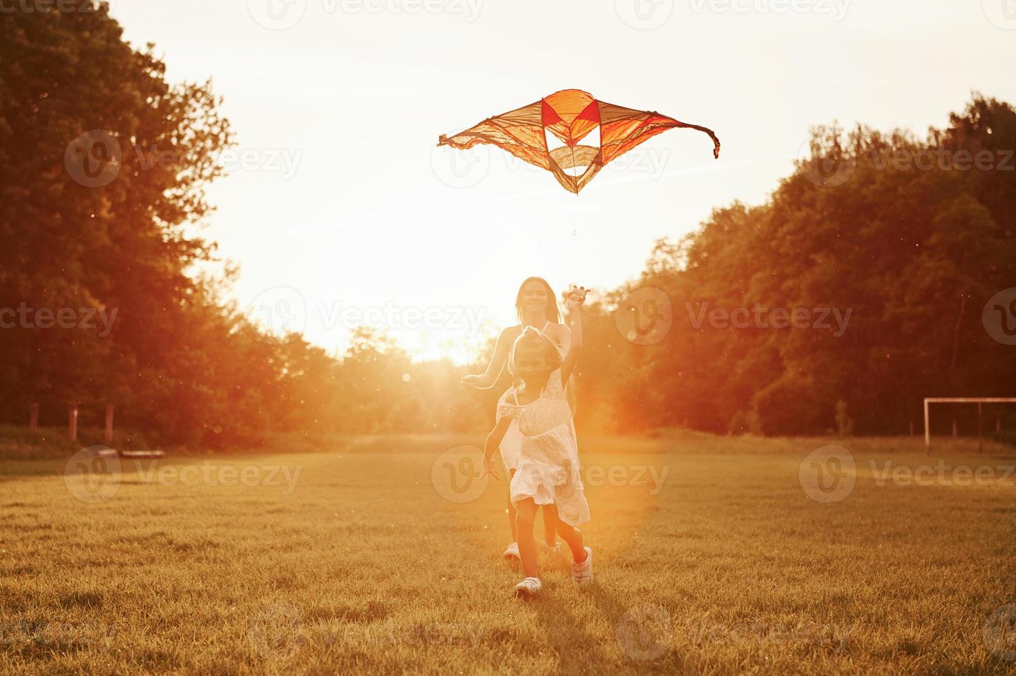 droit dans le ciel. mère et fille s'amusent avec le cerf-volant sur le terrain. belle nature photo