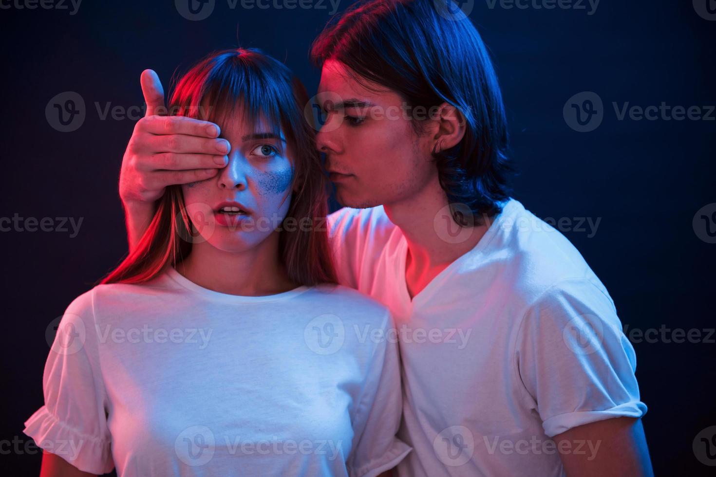 j'ai une surprise pour toi. couple debout dans une pièce sombre avec éclairage au néon rouge et bleu photo