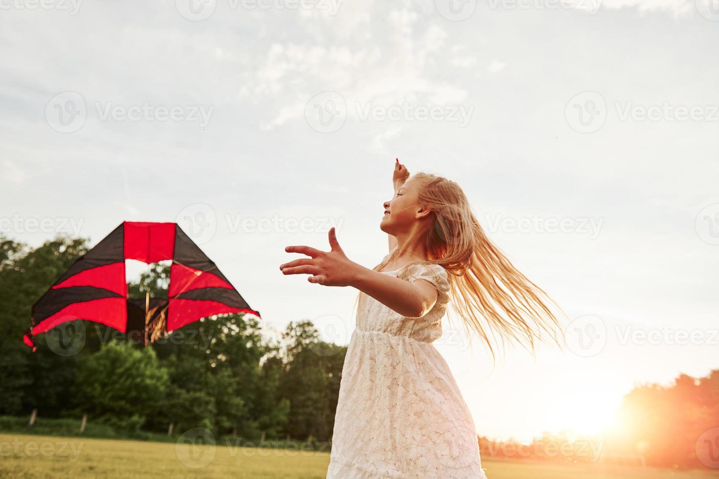 ciel presque dégagé. une fille heureuse en vêtements blancs s'amuse avec un cerf-volant sur le terrain. belle nature photo