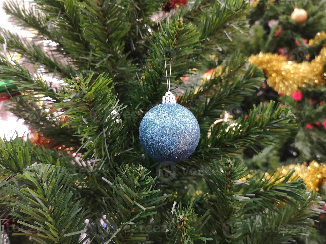 les décorations d'arbre vert de noël décorées ont une boule bleue, des feuilles d'or sur fond flou photo