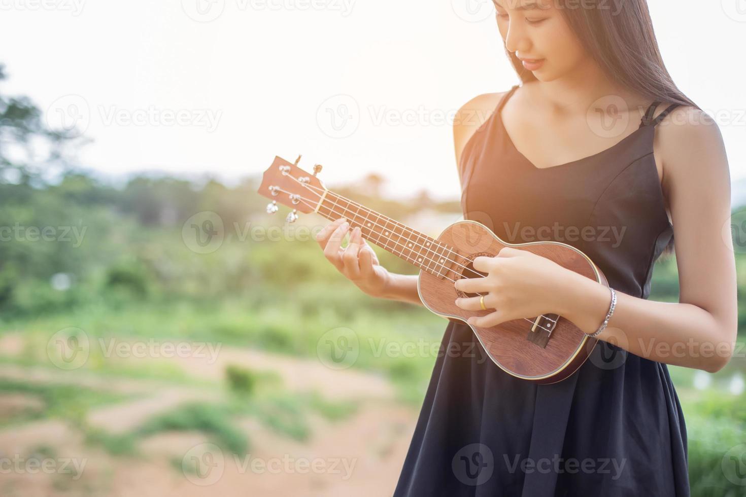 belle femme tenant une guitare sur son épaule, parc naturel été à l'extérieur. photo