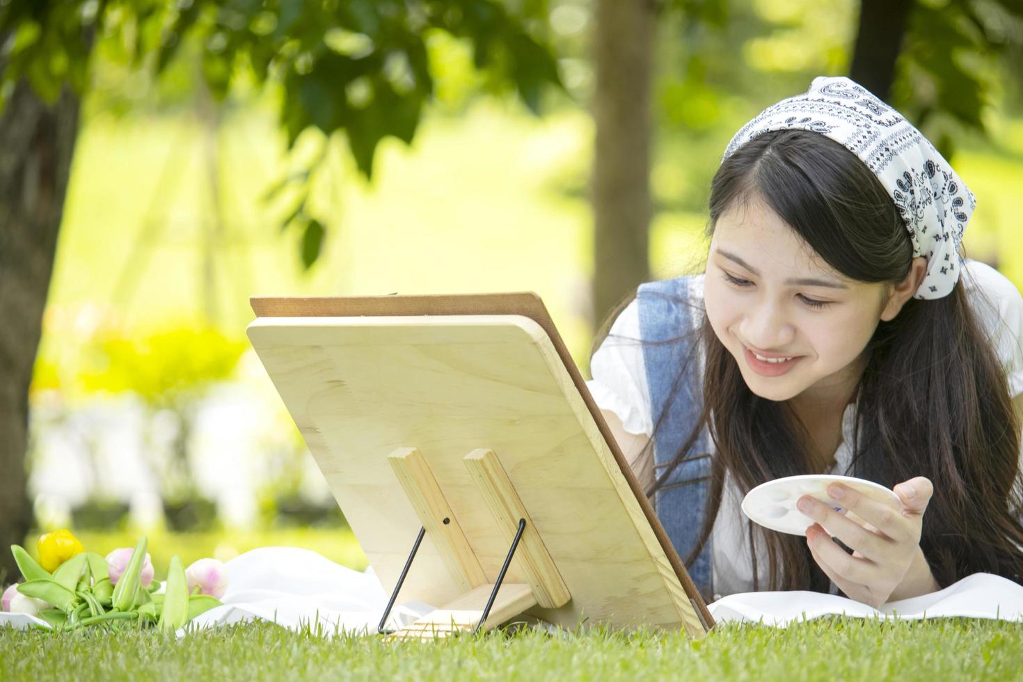 fille asiatique dessinant et souriant joyeusement dans le parc. concept de vie en plein air de joyeuses fêtes photo