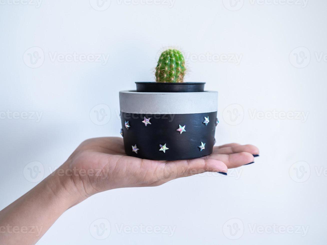 main montrant une jardinière en béton ronde moderne noire avec une plante de cactus verte. pot en béton peint pour la décoration de la maison photo